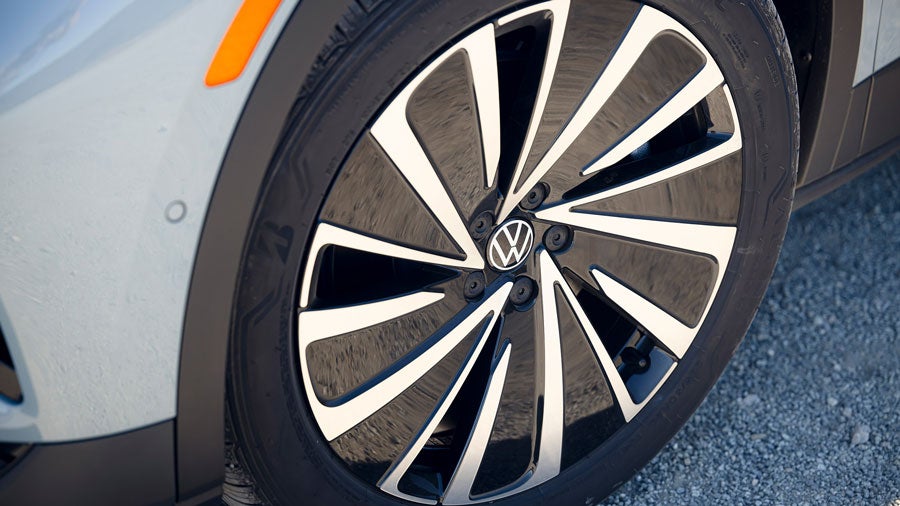 Close-up shot of availble 20” alloy wheel on a parked ID.4 SUV shown in Arctic Blue Metallic.