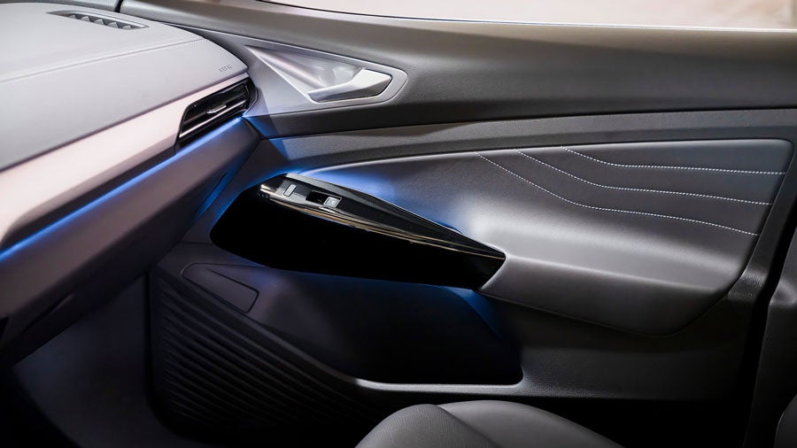 Interior shot of an ID.4 showing multi-colored adjustable ambient lighting on the dash and passenger door handle.